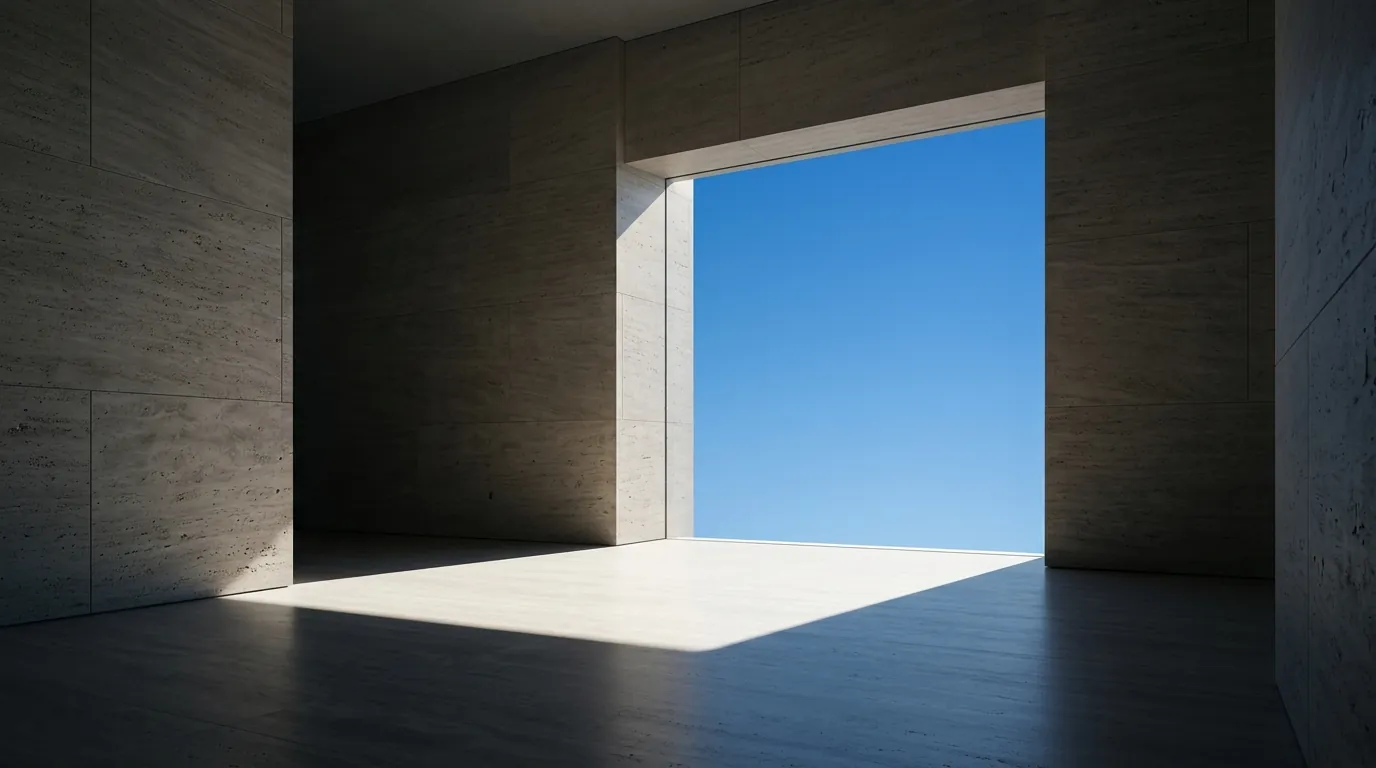 A restrained concrete interior opening towards clear blue sky, with natural light across the floor.